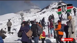 Туристы наслаждаются зимним катанием на лыжах на склонах извергающейся вулкана Этна.