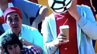 Man gets hit in the face with soccer ball while eating hotdog