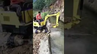 Mini Excavator is working beside a small river bank