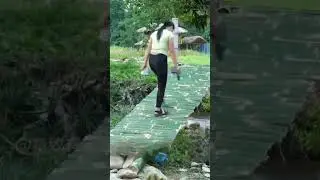 Beautiful young woman builds bamboo bridge alone in the river