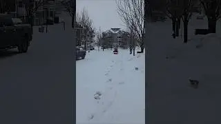 Sidewalk Plow Driving Up Snowy Street