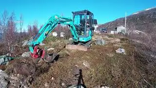 Mini excavator digging trench for main power to an cottage