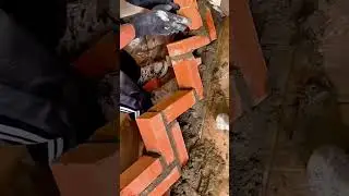 Worker constructing interlocking brick corner with precise alignment