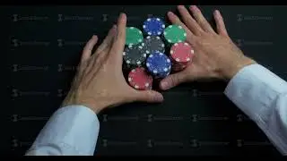 Stack of poker chips and two hands on table. Closeup of poker chips in stacks on green felt card