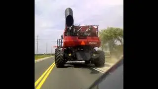 Big red combine driving on road