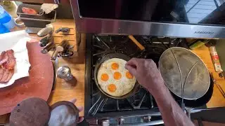 Sunny side up eggs and bacon cooked in cast-iron pan