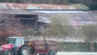 Tractor spreading manure on snow covered farm