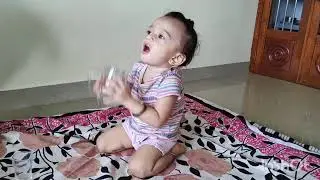 Baby drinking water with glass on his own