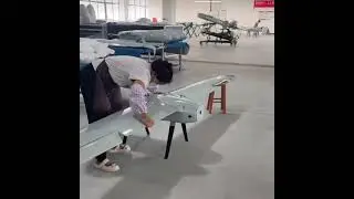 A middle-aged woman worker in a rural Chinese workshop assembles a large unmanned aerial vehicle.