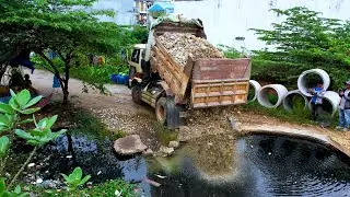 BULLDOZER push stone cover the canal after dump truck unload stone onto the canal