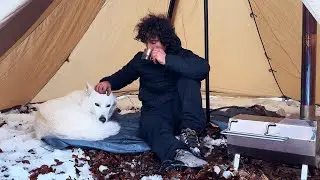 Bivacco in tenda sulla neve con stufa a legna e il mio cane.