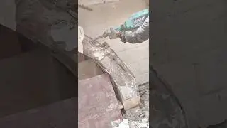 Worker using demolition hammer to break concrete staircase structure