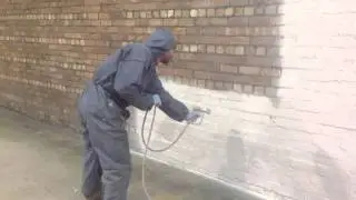 Applying masonry paint to brickwork on industrial unit