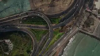 Top down aerial view of cars and trucks driving on a multi level road interchange next to the