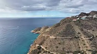Serene seaside settlement with winding paths and white buildings on elevated rocky terrain