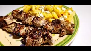 Pork souvlaki (pork cubes on skewers) grilled outside over charcoal