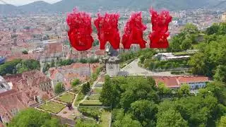 Inscription on video. Graz, Austria. Clock Tower in Graz. The historic city center aerial view. Moun