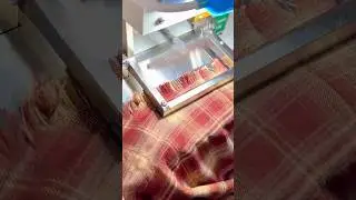 machine precisely trims and frays the edge of a red plaid fabric