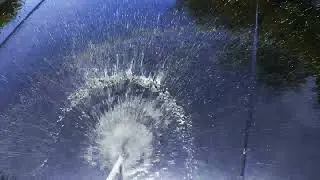 water jet flowing on black car hood at sunny day