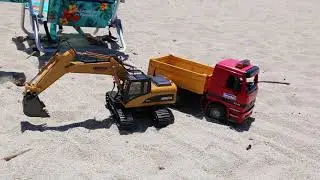 RC toy excavator loading sand at beach