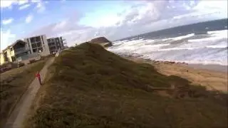 FPV EPP foam model RC flying-wing soaring over a city beach in Australia