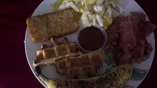 A banana, waffles, bacon, eggs and a hashbrown for breakfast