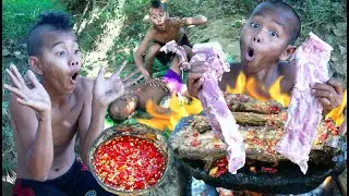 Survival skills. Cooking pork rib on a rock in the rainforest