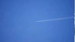 A long range airliner crosses the frame leaving a long contrail. Free HD video footage