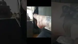 Woman Shoe Dangling In Her Black Shiny Patent Leather High Heels