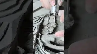 Master craftsman meticulously carves intricate floral details into damp clay surface