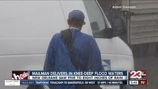 Mailman treads through knee deep water to deliver mail