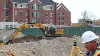 CAT 336E Excavator moving dirt and rocks around a large construction site