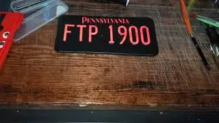 VINYL WRAPPED LICENSE PLATE. REFLECTIVE LETTERING AND MATTE BLACK BACKGROUND