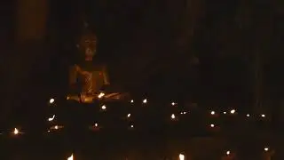 Buddha statue surrounded by candles at Asalha Puja celebrations in Chiang Mai, Thailand