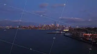 Governors Island aerial view, Downtown Brooklyn skyline at dusk, with lights illuminating buildings
