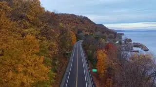 A picturesque aerial view of an autumn road near a lake