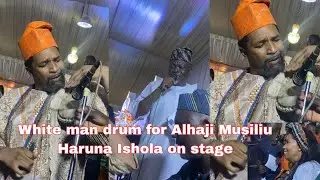A white man plays the drums for Alhaji Musiliu Haruna Ishola on stage.