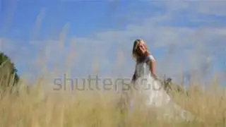 A young blonde bride walking and charmingly smiling in a wheat field