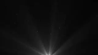Seamless volumetric light from top in dark scene. White lamp rays shine on black background.
