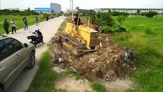 Showing truck dumped soil into dirty water in a garbage lake with bulldozer