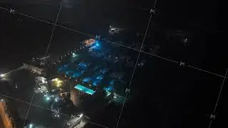 Aerial night shot revealing a luxurious hotel resort with illuminated swimming pool and a marina