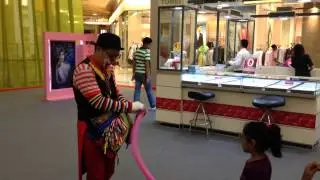 Clown shocked after blowing a balloon burst while the girls laugh