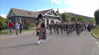 Ellon & District Pipe Band marching through village to the 2023 Braemar Gathering in Scotland