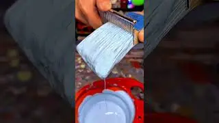 Loading thick blue paint onto a brush evenly by scraping excess for smooth coating application job