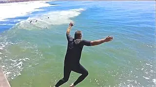 Surfer jumps off Huntington Beach Pier CA. 3-8-2016 during high surf