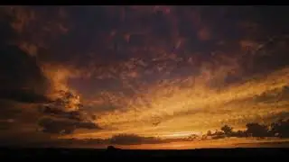Timelapse of wide angle amazing bright yellow and orange sunset sky with moving dark clouds
