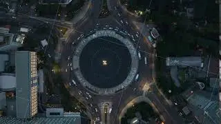 Aerial Birds Eye Overhead Top Down static View of vehicles driving around a busy Selamat Datang