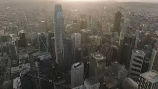 Aerial cinematic footage of modern downtown skyscrapers against setting sun. Financial District in