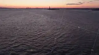 Vibrant sunset casting warm hues across Upper New York Bay, gradually revealing iconic Statue of