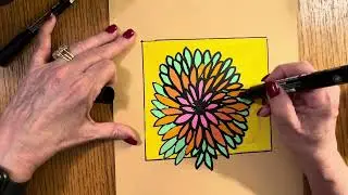 Outlining in black Posca markers a green and orange flower.